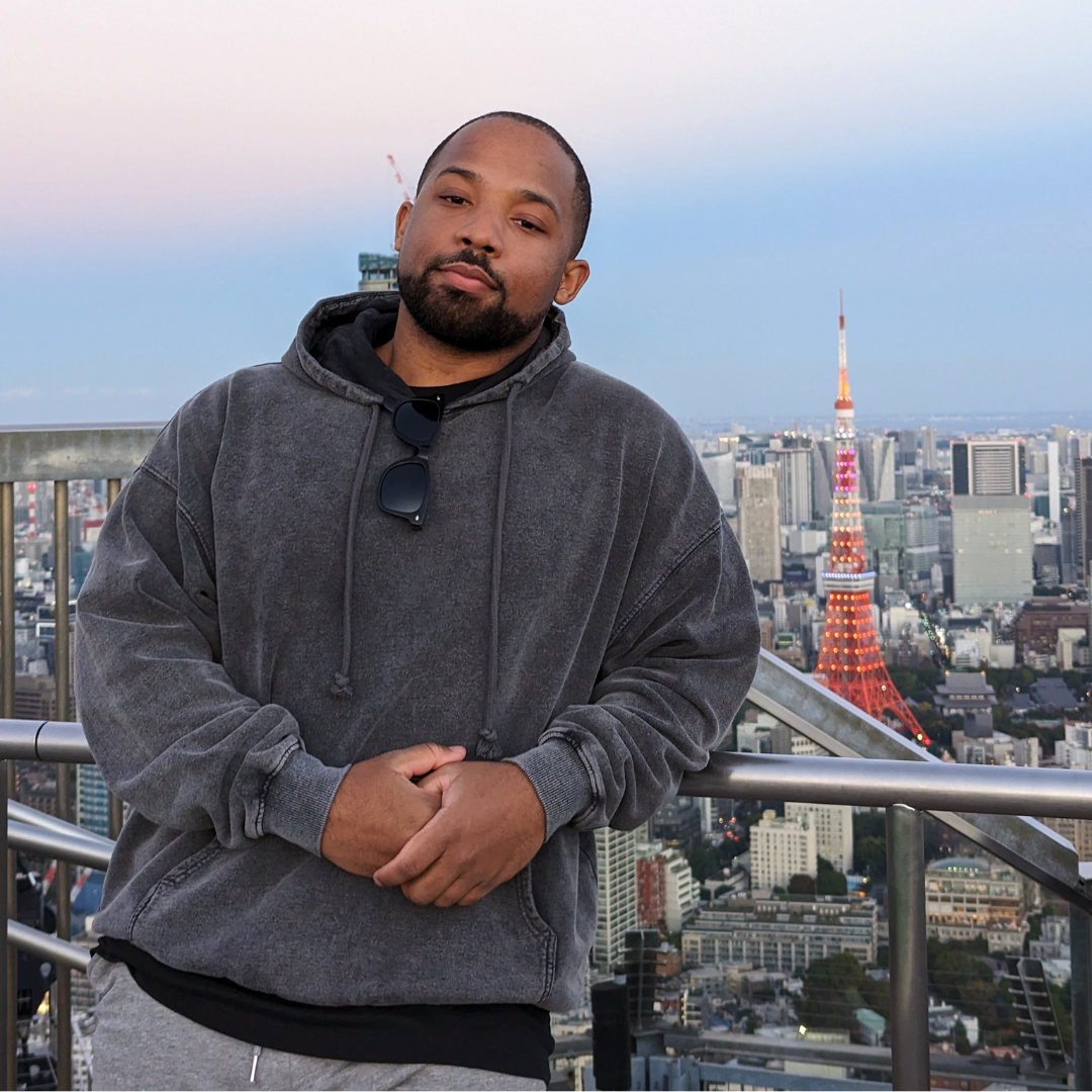 WWT Operations and Administrative Associate Jalen Howard leans against a balcony railing with a skyline behind him.